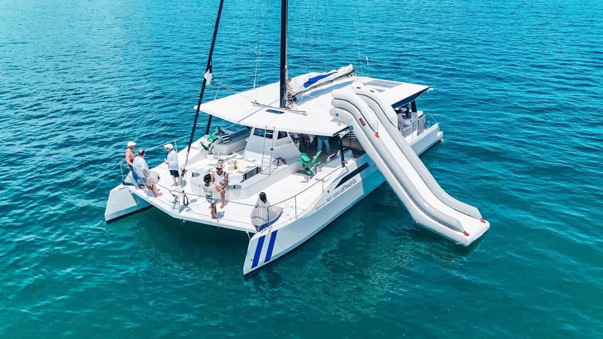 Andaman Satis 55 sailing catamaran with water slide and guests on deck in Phuket
